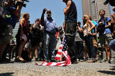 Protesters clash American flag sits at the feet of an anarchist