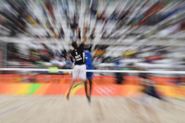 Olympians in motion: Beach Volleyball players jump at volleyball net