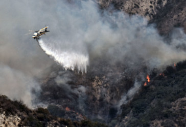 California Wildfires Helicopter drops water on mountainside