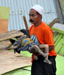 INDONESIA-QUAKE-TSUNAMI man carries the body of a child after an earthquake and tsunami