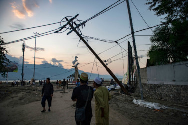 INDONESIA-QUAKE-TSUNAMI People walk along a beach that was hit by a tsunami