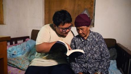 Road to Riches Peng Shui shares his school books with his grandmother.
