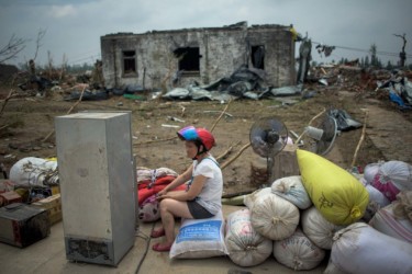 A resident sits in front of a destroyed house after a tornado and severe storms in Funing, China