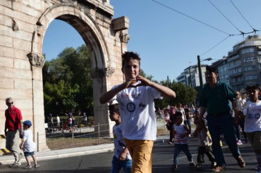 A boy from a refugee camp around Athens shows an heart sign during an event celebrating the Olympic Day and the World Refugee Day