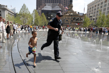 Police take a break Police officer runs through a fountain with a small child