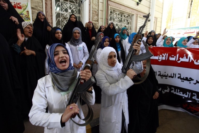 Iraqi Shiite women hold their weapons as they gather to show their willingness to join Iraqi security forces