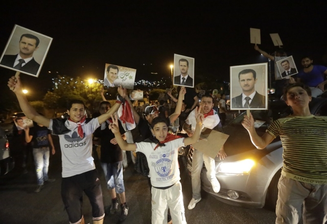 Syrians hold pictures of re-elected Syrian President Bashar al-Assad