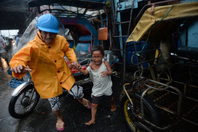 A village official leads a child as he is evacuated from their house at an informal settlers' area as Typhoon Rammasun barrels across Manila