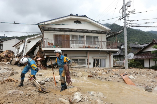 Rescue workers look for survivors at the site of a landslide after heavy rains hit the city of Hiroshima