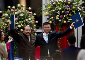 FILE - In this June 14, 2013 file photo, President Daniel Ortega, left, and Chinese businessman Wang Jing hold up a concession agreement for the construction of a multibillion-dollar canal at the Casa de los Pueblos in Managua. The Chinese company granted a concession to build and operate a transoceanic canal across Nicaragua said Thursday, Jan. 8, 2014, that the project will create jobs for 25,000 Nicaraguans and 25,000 more for foreigners. (AP Photo/Esteban Felix, File)