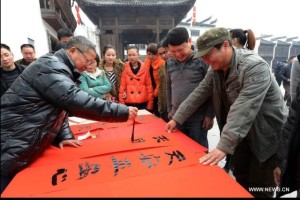 Zhan Ruitian (L, front), a calligraphy enthusiast, writes Spring Festival Couplets in Jiangwan Village of Wuyuan County, east China's Jiangxi Province, Feb. 4, 2013. Xinhua/Song Zhenping