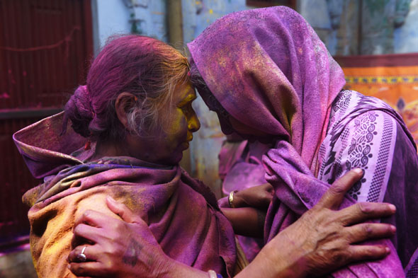 Two Indian widows touch their foreheads as they celebrate Holi or the "festival of colors" in Vrindavan on March 3, 2015.  Widows congregated on a small patio of the ashram in which they live and danced and played with colored powder to celebrate the occasion. The widows of this and other ashrams in this northern town are sponsored by Sulabh International, an NGO which funds most of their needs.  Shunned from society when their husbands die, not for religious reasons, but because of tradition, many Indian widows have been ostracized from society and no longer live with their families and are forced to beg for food. Almost 2,000 of the estimated 34 million widows currently living in India live in Vrindavan and benefit from the welfare extended by Sulabh.    AFP/ Roberto Schmidt