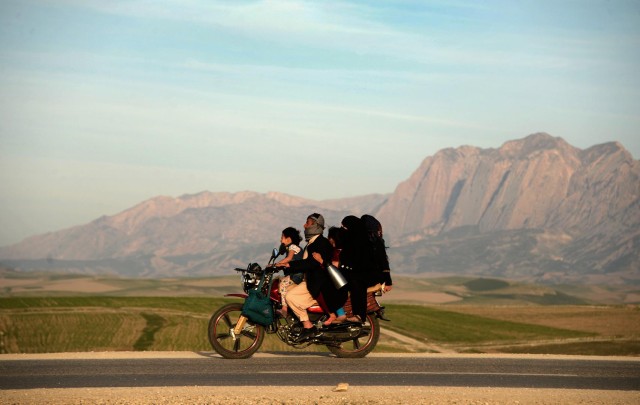 In this photograph taken on March 22, 2015, an Afghan family travel on a motorcycle as they travel to celebrate Nowruz which marks the Afghan New Year on the outskirts of Mazari-i-Sharif. Nowruz, one of the biggest festivals of the war-scarred nation, marks the first day of spring and the beginning of the year in the Persian calendar. Nowruz is calculated according to a solar calendar, this coming year marking 1394.  (AFP/ Farshad Usyan)