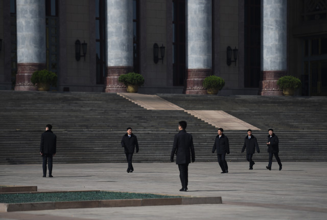 Chinese soldiers dressed as ushers clear the area in front of the Great Hall of the People  in Beijing after a meeting of officials on March 2, 2015. The Great Hall of the People is the venue for meetings of China's Communist Party-controlled legislature, the National People's Congress (NPC), which starts in the capital this week with the "rule of law" high on the agenda.   AFP PHOTO / Greg BAKER