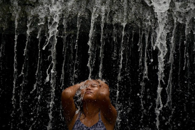 A woman enjoys the water overflowing from a defunct but still watery reservoir called the Wawa dam in Montalban in Manila on March 22, 2015.  The Philippines observes World Water day on March 22, a global event that focuses on finding access to clean and safe water.    (AFP/ Noel Celis)