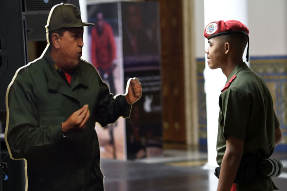 A member of the presidential guard stares at an image depicting late Venezuelan President Hugo Chavez during the opening ceremony of the Petrocaribe  summit in Caracas on March 6, 2015.  AFP/ Juan Barreto