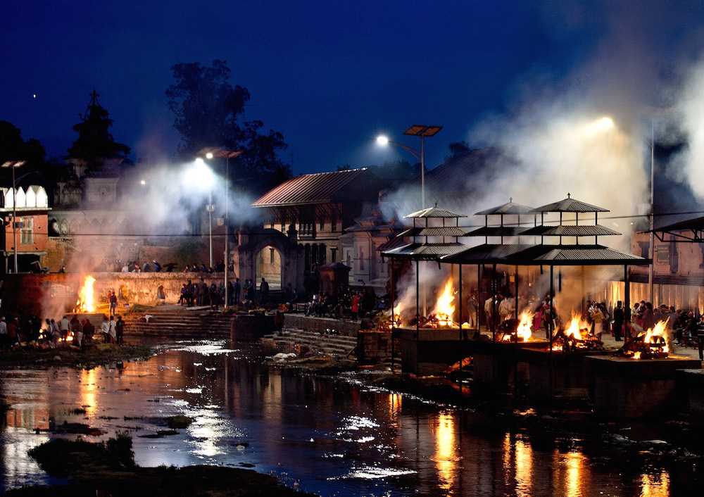 Funeral pyres burn during a mass cremation of earthquake victims on the banks of Bagmati river at the Pasupathinath temple in Kathmandu on April 29, 2015.  The United Nations appealed for $415 million for Nepal, saying it urgently needs more funds to provide relief to people affected by a devastating earthquake.      AFP PHOTO / MANAN VATSYAYANA