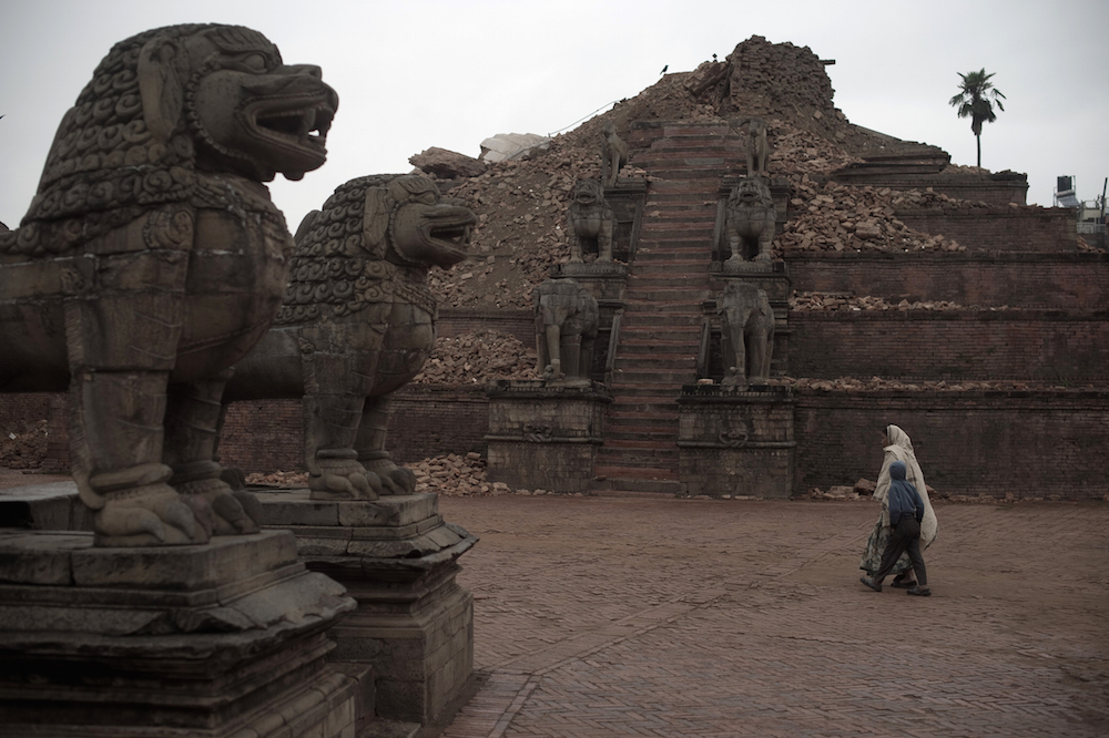 Residents walk through temples in the UNESCO world heritage site of Bhaktapur on the outskirts of the Nepalese capital Kathmandu on April 30, 2015. AFP PHOTO / Nicolas ASFOURI