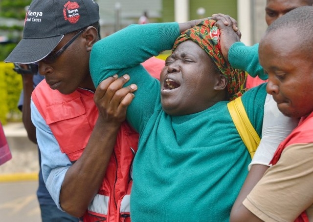 Members of the Red Cross help a relative of one of the students massacred by Somalia's Shebab Islamists at a Kenyan university at the Chiromo funeral parlour in the Kenyan capital, Nairobi, on April 3, 2015. The bodies of dozens of students massacred by Somalia's Shebab Islamists at a Kenyan university in Garissa arrived in the capital today, as grieving relatives faced a desperate wait to receive the remains of their loved ones. AFP PHOTO / TONY KARUMBA