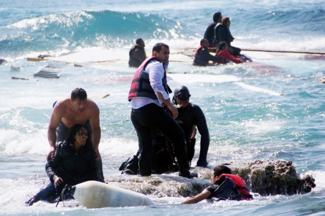 Local residents and rescue workers help a migrant woman after a boat carrying migrants sank off the island of Rhodes, southeastern Greece, on April 20, 2015. At least three people, including a child, died when a boat carrying more than 80 migrants sank off the Greek island of Rhodes today, police said. AFP PHOTO / EUROKINISSI / ARGIRIS MANTIKOS