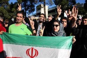 Iranians flash the victory sign as they hold their country's flag while waiting for arrival of Foreign Minister Mohammad Javad Zarif from Lausanne, Switzerland, at the Mehrabad airport in Tehran, Iran, Friday, April 3, 2015. Iran and six world powers reached a preliminary nuclear agreement Thursday outlining commitments by both sides as they work for a comprehensive deal aiming at curbing nuclear activities Tehran could use to make weapons and providing sanctions relief for Iran. (AP Photo/Ebrahim Noroozi)