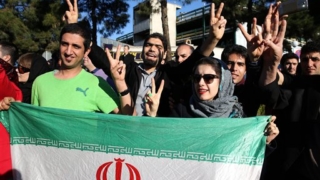 Iranians flash the victory sign as they hold their country's flag while waiting for arrival of Foreign Minister Mohammad Javad Zarif from Lausanne, Switzerland, at the Mehrabad airport in Tehran, Iran, Friday, April 3, 2015. Iran and six world powers reached a preliminary nuclear agreement Thursday outlining commitments by both sides as they work for a comprehensive deal aiming at curbing nuclear activities Tehran could use to make weapons and providing sanctions relief for Iran. (AP Photo/Ebrahim Noroozi)