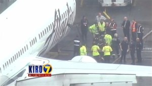 In this frame from video, workers walk with a Menzies Aviation cargo worker after the worker was removed from the cargo hold of an Alaska Airlines passenger airplane, Monday, April 13, 2015, at Seattle-Tacoma International Airport, in Seattle. The Los Angeles-bound flight had to return to Seattle when noises were heard from the worker in the hold as the plane took flight. (KIRO 7 via AP) MANDATORY CREDIT; LOCAL TV OUT