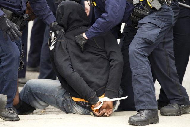 Baltimore police officers detain a demonstrator after clashes with police, after the funeral of Freddie Gray, on Monday, April 27, 2015, at New Shiloh Baptist Church in Baltimore. Gray died from spinal injuries about a week after he was arrested and transported in a Baltimore Police Department van. (AP Photo/Jose Luis Magana)