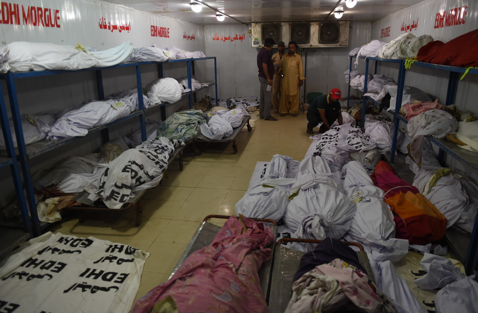 Relatives of heatwave victims stand as dead bodies are seen in the the cold storage of the EDHI morgue in Karachi on June 21, 2015. A heatwave has killed at least 45 people in Pakistan's largest city of Karachi, officials said June 21, as residents grapple with frequent power outages and water scarcity during the Muslim fasting month of Ramadan. (AFP PHOTO / ASIF HASSAN)