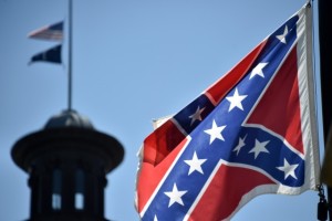The South Carolina and American flags flying at half-staff behind the Confederate flag erected in front of the State Congress building in Columbia, South Carolina on June 19, 2015. Police captured the white suspect in a gun massacre at one of the oldest black churches in Charleston in the United States, the latest deadly assault to feed simmering racial tensions. Police detained 21-year-old Dylann Roof, shown wearing the flags of defunct white supremacist regimes in pictures taken from social media, after nine churchgoers were shot dead during bible study on Wednesday. AFP PHOTO/MLADEN ANTONOV