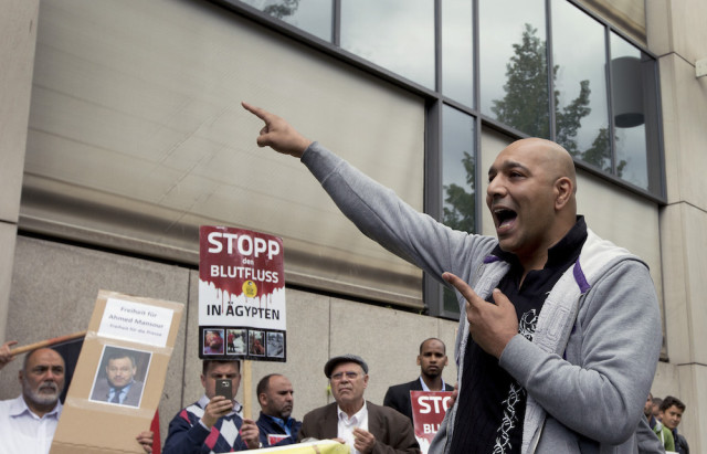 A man speaks in front of a court to support the release of the journalist Ahmed Mansour in Berlin, Germany, Sunday, June 21, 2015. Poster at center reads: "Stop the blood flow in Egypt".  (AP Photo/Michael Sohn)