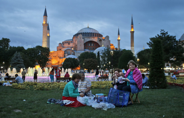 People break their fast backdroped by the Byzantine-era Hagia Sophia, in the historic Sultanahmet district of Istanbul, Turkey, Thursday, June 18, 2015 on the first day of the fasting month of Ramadan. Muslims throughout the world are marking Ramadan - a month of fasting during which the observants abstain from food, drink and other pleasures from sunrise to sunset. After an obligatory sunset prayer, a large feast known as 'iftar' is shared with family and friends. (AP Photo/Emrah Gurel)