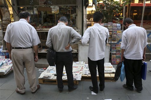 Iranian men scan newspapers at a newsstand in downtown Tehran, Iran, Sunday, July 12, 2015. Negotiators at the Iran nuclear talks plan to announce Monday that they've reached a historic deal capping nearly a decade of diplomacy that would curb the country's atomic program in return for sanctions relief, two diplomats told The Associated Press on Sunday. But they cautioned that final details of the pact were still being worked out and a formal agreement must still be reviewed by leaders in the capitals of Iran and the six world powers at the talks. (AP Photo/Vahid Salemi)