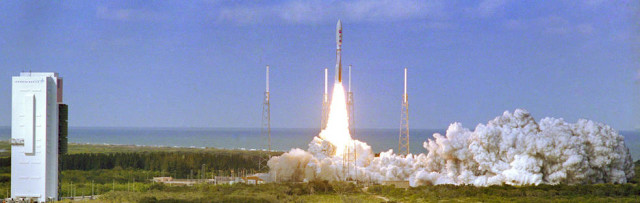 Photo by NASA. With the blue Atlantic Ocean as backdrop, smoke and steam fill the launch pad, at right, as NASA’s New Horizons spacecraft roars into the sky aboard an Atlas V rocket. January 19, 2006