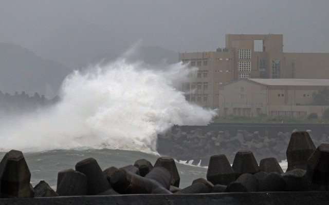 Giant waves crash into the coastline next to National Taiwan Ocean University (R) in Keelung as Typhoon Chan-hom brings rain to northern Taiwan on July 10, 2015.  Taiwan was bracing for fierce winds and torrential rains on July 10 as Typhoon Chan-hom gained momentum and the island's stock market, schools and offices closed in preparation for the storm.     AFP PHOTO / Sam Yeh