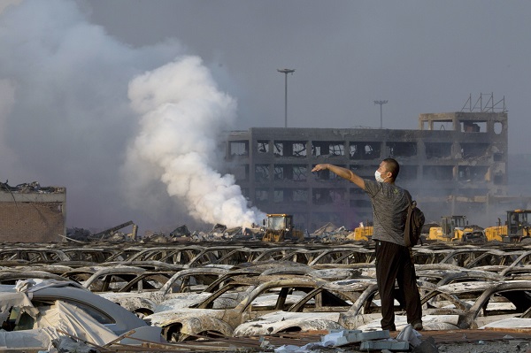 In this photo taken Thursday, Aug. 13, 2015, a man walks through the site of an explosion at a warehouse in northeastern China's Tianjin municipality. (AP Photo/Ng Han Guan)
