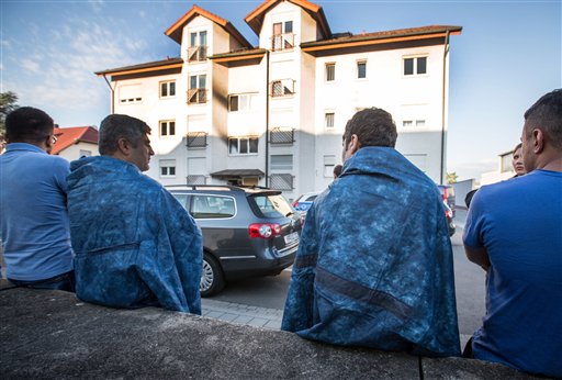 Residents sit in front of an accommodation for asylum seekers in Heppenheim, Germany, Friday Sept. 4, 2015. German police say they're investigating a fire at a home for asylum seekers in the western state of Hesse in which five people were injured. (Frank Rumpenhorst/DPA via AP)