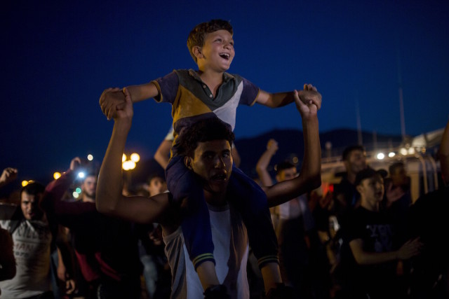 Refugees and migrants take part in a protest demanding the authorities to let them go to Athens and continue their trip towards Northern Europe, at the port of Mytilene, on the northeastern Greek island of Lesbos, on Saturday, Sept. 5, 2015. Earlier many of them confronted the police as they attempted to get onboard a ship bound to Athens' port of Piraeus. (AP Photo/Santi Palacios)