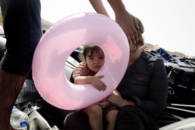 A Syrian family react after they arrived with others aboard a dinghy from Turkey, on the island of Lesbos, Greece, Monday, Sept. 7, 2015. The island of some 100,000 residents has been transformed by the sudden new population of some 20,000 refugees and migrants, mostly from Syria, Iraq and Afghanistan. (AP Photo/Petros Giannakouris)