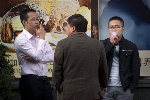 In this Thursday, Oct. 8, 2015 photo, men smoke cigarettes outside of an office building in Beijing. Research published in the medical journal The Lancet says one in three of all the young men in China are likely to die from tobacco, but that the number can fall if the men quit smoking. (AP Photo/Mark Schiefelbein)