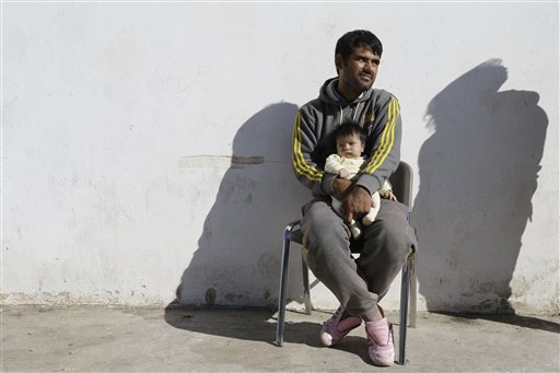An Afghan father holds his baby at the Galatsi Olympic Hall in Athens, Wednesday, Nov. 4, 2015. The disused facility, which used during the Athens Olympics 2004, reopened a month ago for migrants as more than 600,000 people have arrived in Greece so far this year trying to head for more prosperous European Union countries in the north. (AP Photo/Thanassis Stavrakis)