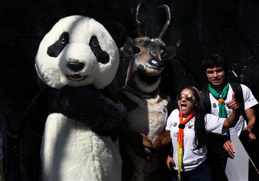 People protest next to characters dressed as wild animals during a march against climate change near the Monument to the Revolution, in Mexico City, Sunday, Nov. 29, 2015. The march came as leaders of 150 countries prepare to converge on Paris to launch two weeks of high-stakes talks on global warming. (AP Photo/Marco Ugarte)