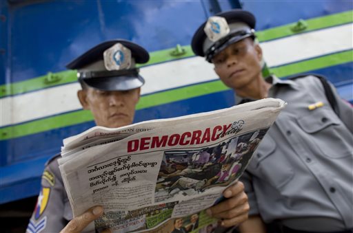 Police officers read a copy of the newspaper "Democracy Today" in Yangon, Myanmar, Wednesday, Nov. 11, 2015. Myanmar's opposition leader Aung San Suu Kyi has won her parliamentary seat, official results showed Wednesday, leading a near total sweep by her party that will give the country its first government in decades that isn't under the military's sway. (AP Photo/ Gemunu Amarasinghe)