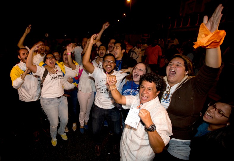 Opposition supporters celebrate in Caracas, Venezuela, early Monday, Dec. 7, 2015. Venezuela's opposition has won control of the National Assembly by a landslide. Election officials say Venezuela's opposition won at least 99 seats in the incoming 167-seat National Assembly and the ruling socialist party 46.(AP Photo/Fernando Llano)