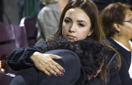 Michelle Zamora , left, is comforted by her sister, Melissa Zamora, of San Bernardino,  at a vigil at San Manuel Stadium Thursday, Dec. 3, 2015, in remembrance of the 14 people lost Wednesday in the San Bernardino mass shooting. (Tom Tingle/The Arizona Republic via AP)