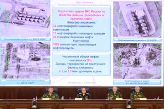 Defence ministry officials sit under screens with satellite images on display during a briefing in Moscow, Russia, December 2, 2015. 
