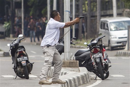 A plainclothes police officer aims his gun at attackers during a gun battle following explosions in Jakarta, Indonesia Thursday, Jan. 14, 2016. Attackers set off explosions at a Starbucks cafe in a bustling shopping area in Indonesia's capital and waged gunbattles with police Thursday, leaving bodies in the streets as office workers watched in terror from high-rise buildings. (AP Photo)