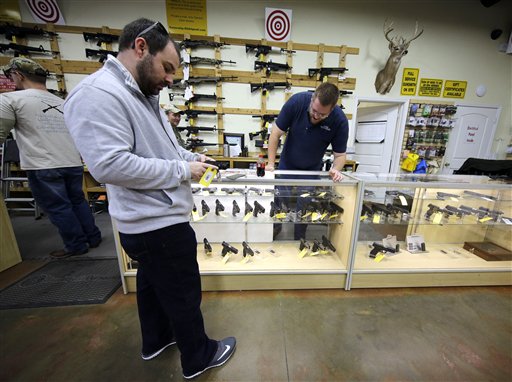 David Foley, center, looks as a handgun while shopping at the Spring Guns and Amo store Monday, Jan. 4, 2016, in Spring, Texas. President Barack Obama defended his plans to tighten the nation's gun-control restrictions on his own, insisting Monday that the steps he'll announce fall within his legal authority and uphold the constitutional right to own a gun. (AP Photo/David J. Phillip)