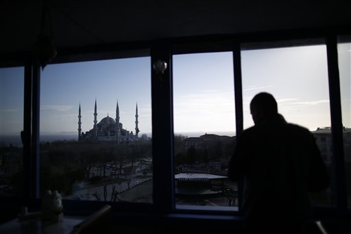 Backdropped by the Sultan Ahmed Mosque, better known as the Blue Mosque, a man watches from inside a building the area of an explosion, in the historic Sultanahmet district of Istanbul, t Tuesday, Jan. 12, 2016.(AP Photo/Emrah Gurel)