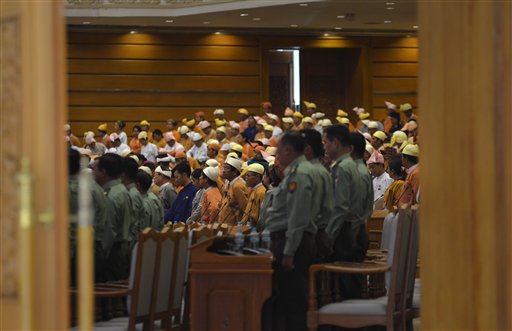 Lawmakers of the National League for Democracy party, far and appointed Myanmar military lawmakers, foreground stay stand after a session at Myanmar parliament in Naypyitaw, Myanmar, Monday, March 14, 2016. Myanmar's parliament vote on Tuesday, March 15 to pick the country's next president from a group of three final candidates, including a front runner who is a longtime confidant of Nobel laureate Suu Kyi. (AP Photo/Aung Shine Oo)